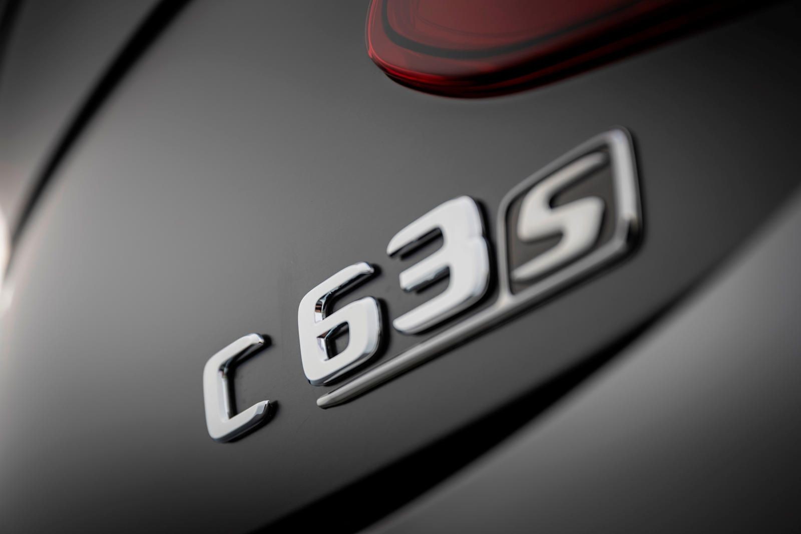 Close-up view of a C 63 S badge on a sleek, dark-colored vehicle.