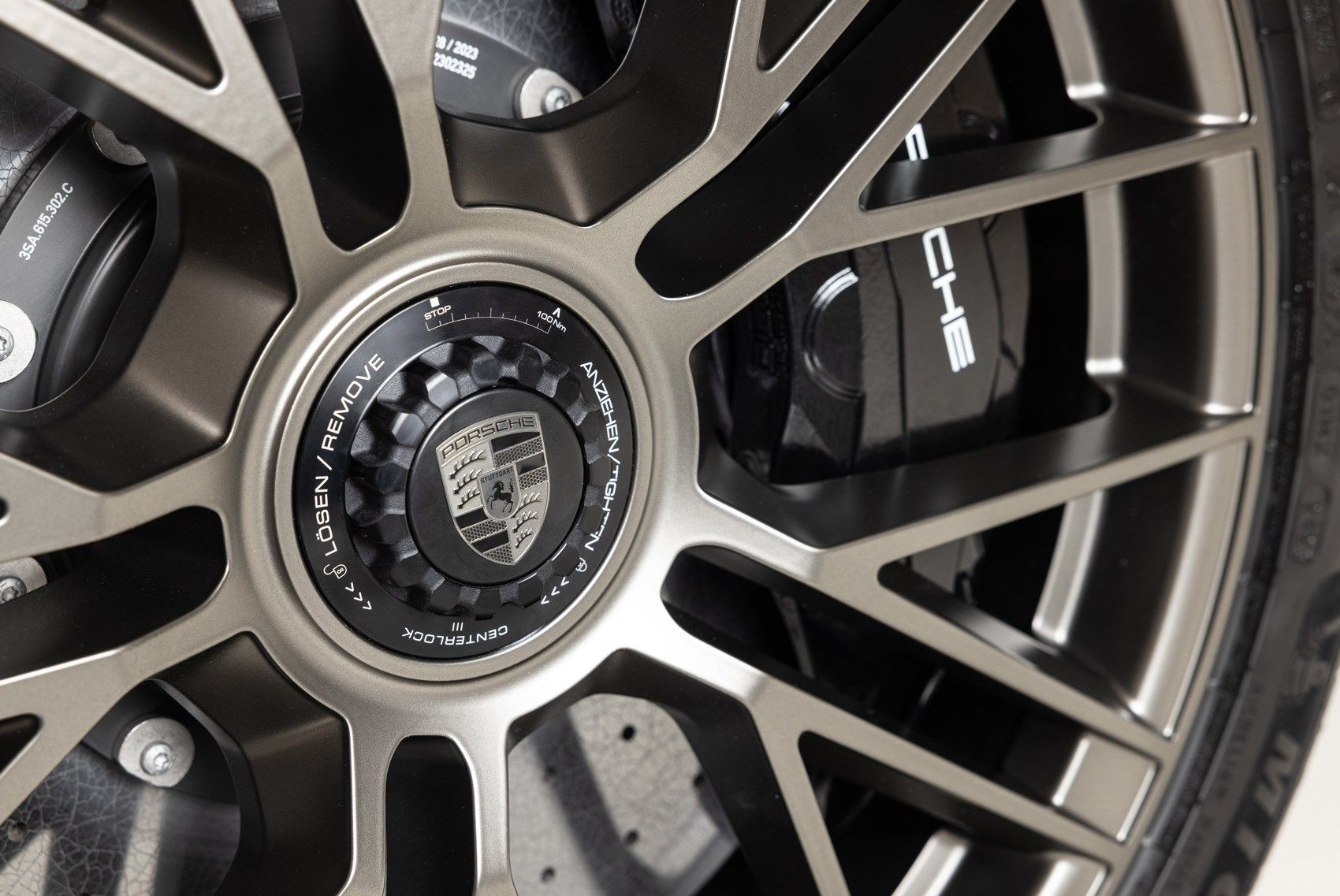 Close-up view of a high-performance car wheel with the Porsche emblem at the center.